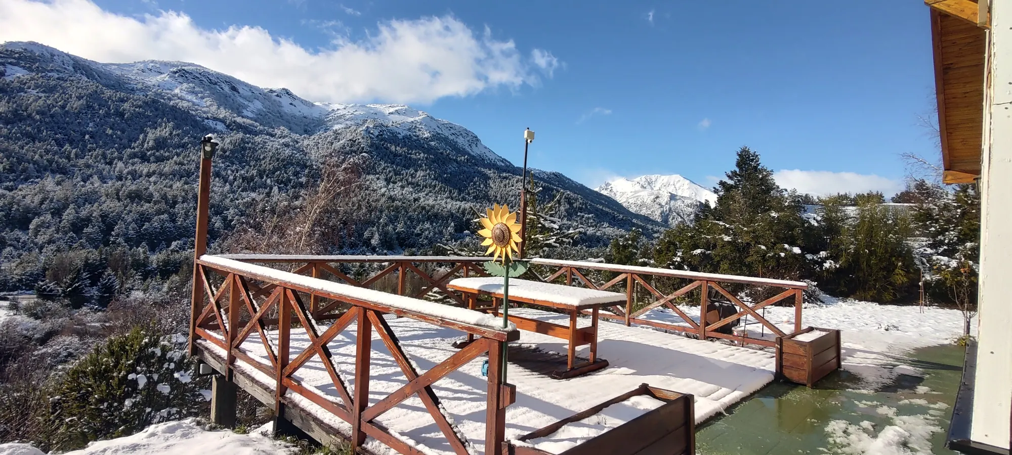Deck de la cabaña con vista a las montañas nevadas y el bosque en Villa Los Coihues, Bariloche