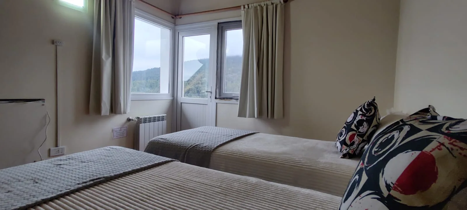 Dormitorio en planta alta con dos camas y ventana con vista al bosque en Villa Los Coihues, Bariloche